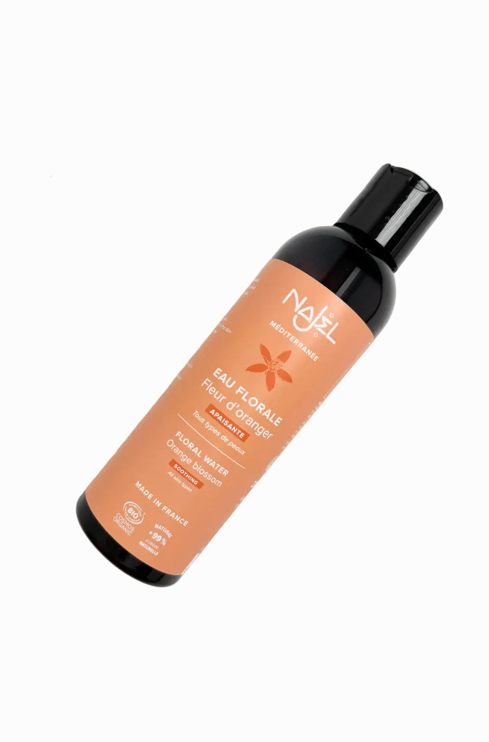 Nati hair mist bottle on a light background with flowers