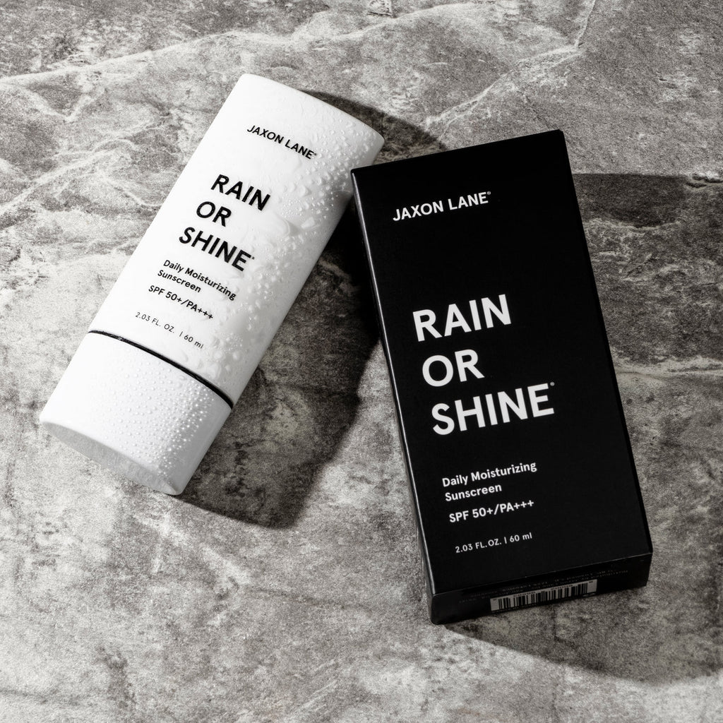 Jaxon Lane Rain or Shine sunscreen bottle and packaging on a stone surface