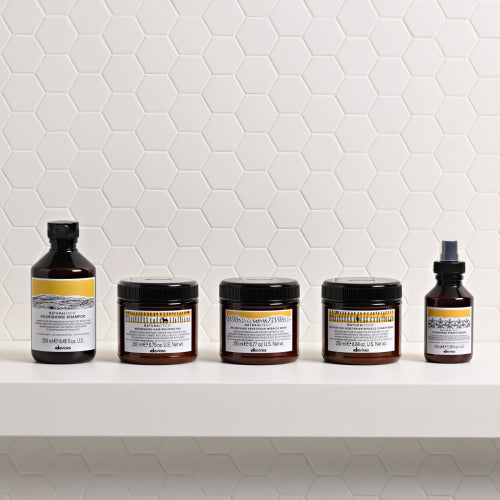 Set of Davines hair care products on a white shelf with a white tiled wall background