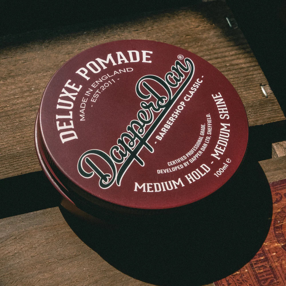 Daiper Dan Deluxe Pomade container on a wooden surface