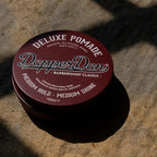 Dapper Dan pomade container on a stone surface
