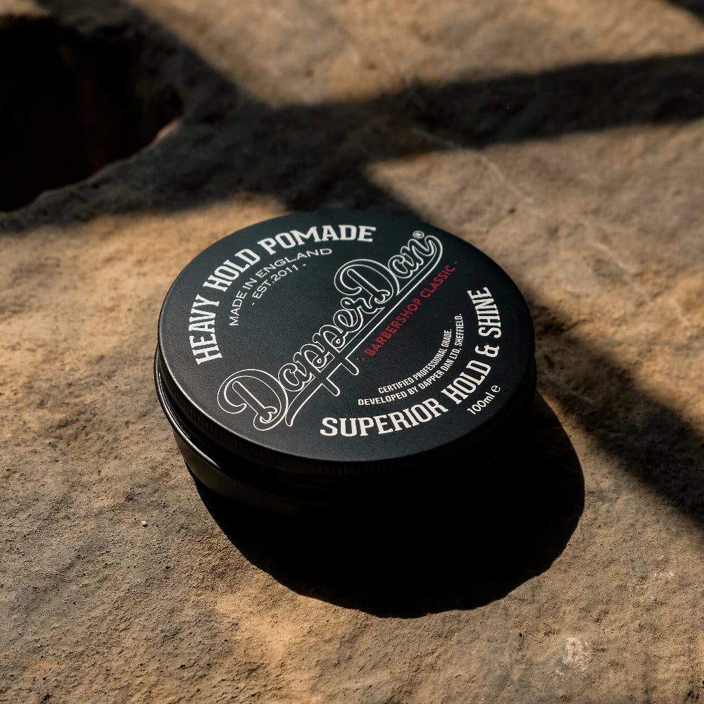Black container of Dapper Dan Heavy Hold Pomade on a textured stone surface