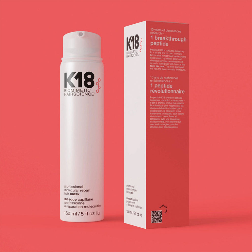 A bottle of K18 Professional Mask placed next to its packaging box against a red background.
