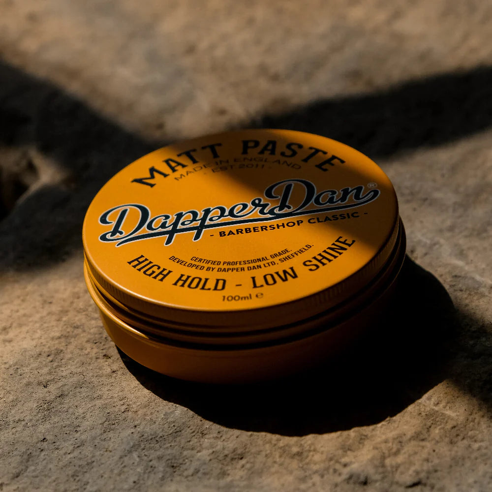 Yellow container of Dapper Dan Matt Paste on a textured surface