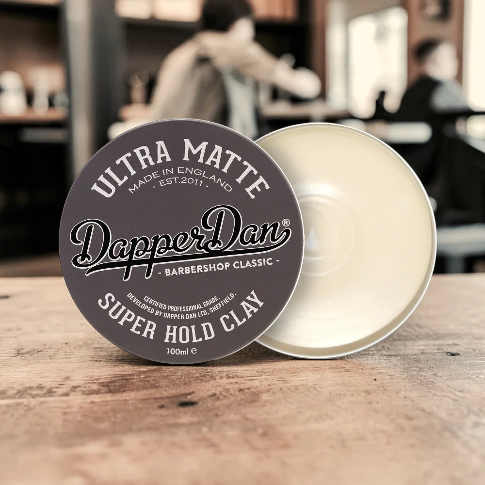 Dapper Dan Super Hold Clay container on a wooden surface with a blurred background
