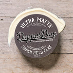 Dapper Dan Ultra Matte Super Hold Clay container on a wooden surface