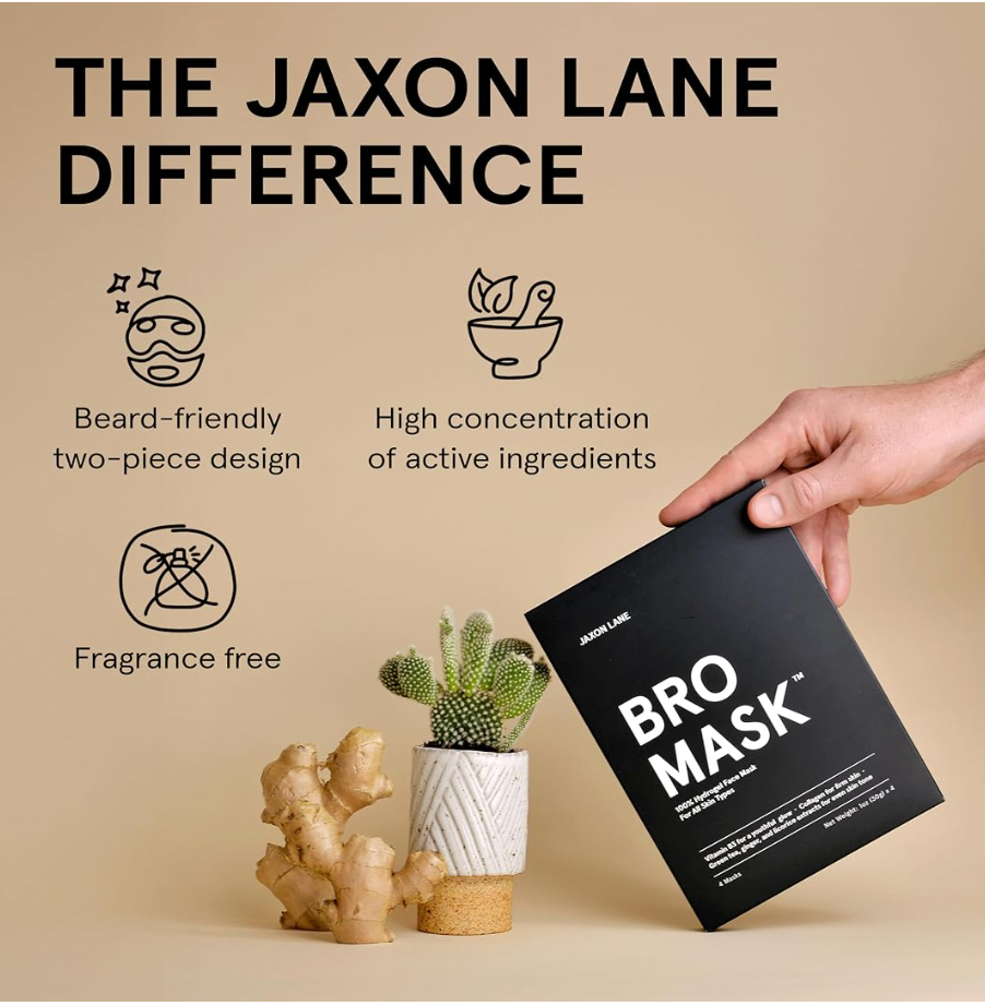 A hand holds a black Jaxon Lane Bro Mask package against a beige background with promotional text and icons about beard-friendly two-piece design, high concentration of active ingredients, and fragrance-free formula. Small props including ginger and a cactus sit below.