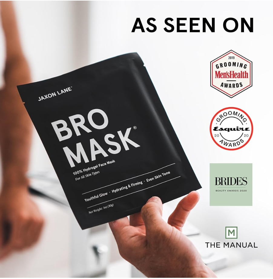 A hand holds a black Jaxon Lane Bro Mask face mask pouch in a bright indoor setting. The image includes 'AS SEEN ON' text and logos for Grooming Men's Health Awards, Esquire Awards, Brides Beauty Fair 2023, and The Manual.