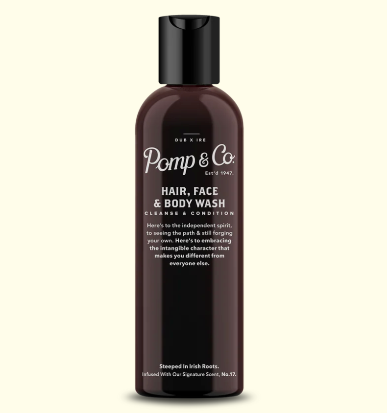 A dark brown bottle of Pomp & Co Hair, Face & Body Wash with a black cap, centered on a light cream background.