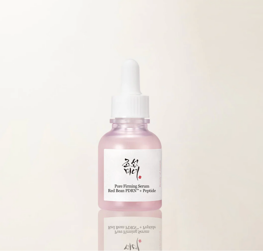 A pink glass dropper bottle of Pure Firming Serum with a white label and white dropper cap, centered on a clean off-white background with a soft reflection below.